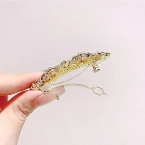 Dettaglio del fermaglio per capelli dorato con strass scintillanti tenuto in mano