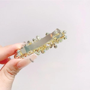Dettaglio di fermaglio per capelli a fiore con strass scintillanti e perle dorate