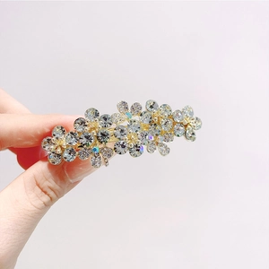 Dettaglio di un fermaglio per capelli dorato con strass scintillanti e fiori a mano