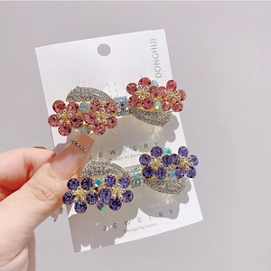 Detail view of purple and pink crystal flower hair clips with rhinestones on card
