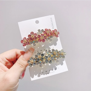 Dettaglio di fermagli per capelli floreali con strass colorati su una scheda espositiva