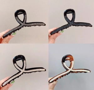 Dettaglio di quattro grandi mollette per capelli con strass nei colori grigio e blu