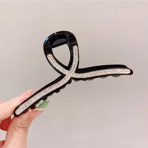Macro di una grande clip per capelli nera con strass argentati brillanti e lucidi