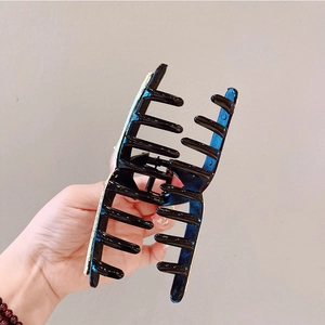 Dettaglio di una grande molletta nera per capelli con decorazioni di glitter dorati lucidi