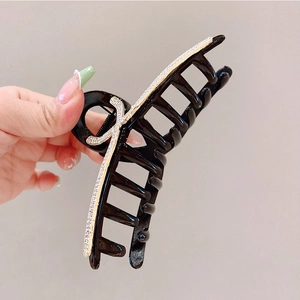Dettaglio del grande fermaglio per capelli nero con inserto dorato e strass scintillanti