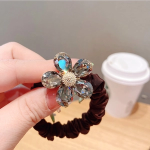 Vue détaillée de la fleur en cristal sur un chouchou plissé marron pour cheveux