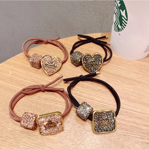 Detail of high-elastic hair ties with heart and square crystal charms on wood