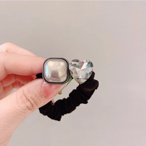 Détail d'un chouchou élastique avec cube argenté et breloque en cristal en forme de cœur