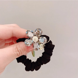 Détail d'un élastique à cheveux plissé noir avec breloque fleurie en cristal