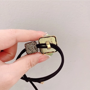 Detail of high-elastic black hair tie with square gold alloy and sparkling rhinestones