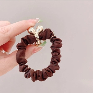 Détail du chouchou marron café en tissu brillant avec boucle fleur en métal doré