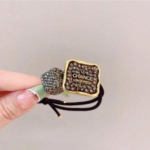Macro shot of luxury hair tie featuring rhinestone-inlaid square and sphere charms