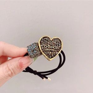 Detailed macro view of black elastic hair tie featuring a sparkling heart crystal charm