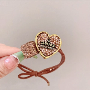 Macro shot of handmade hair tie with champagne gold heart and square full diamond charms