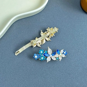 Détail de la pince à cheveux fleurie en strass étincelants et du fermoir en métal doré