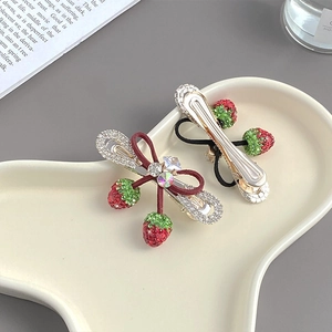 Détail de la pince à cheveux fraise avec nœud en velours rouge et pendentif en strass