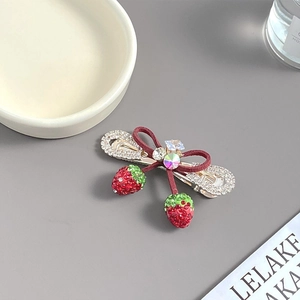 Détails d'une pince à cheveux nœud fraise en velours avec strass et pendentifs élégants