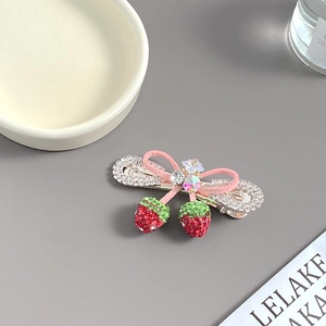 Détail de la pince à cheveux fraise avec nœud rose et strass brillants décoratifs