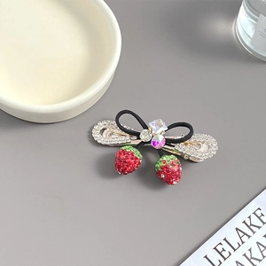 Détail de la pince à cheveux fraise avec strass rouges et un nœud noir