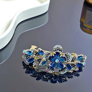 Détail d'une pince à cheveux élégante en alliage doré avec strass bleus et motif floral