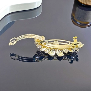 Détail de la pince à cheveux élégante en forme de fleur avec strass et base dorée