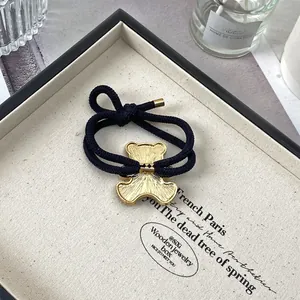Détail de l'élastique bleu marine avec pendentif ours doré sur plateau à bijoux beige