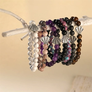 Detailed close-up of handmade stone bead bracelets hanging on white natural wood branches