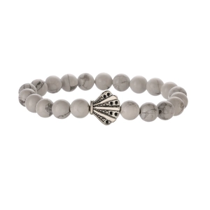 Close-up of white turquoise beaded bracelet with silver shell charm and marble texture