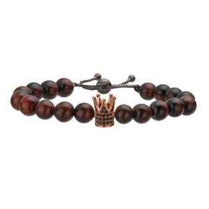 Macro shot of tiger eye beads with rose gold crown charm and woven adjustable cord