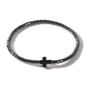 Detailed view of elastic beaded bracelet featuring black cylinder stones and a cross pendant