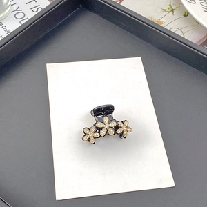 Detailansicht kleine schwarze Haarklammer mit drei goldenen Strassblumen für Damen