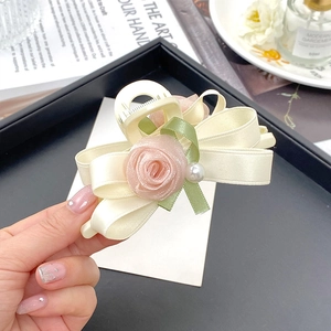 Detail einer eleganten Haarklammer mit Netzrose, Satinschleife und Perle in der Mitte