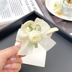 Detailansicht der cremefarbenen Stoffrose und Champagner-Schleife für elegante Haarklammern