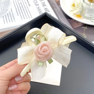 Detail-Ansicht einer Haarklammer mit cremefarbener Organza-Schleife und rosa Stoffrose