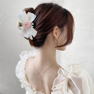 Eleganter Haarklammer mit Netzschleife und rosa Stoffrose am Haar einer Frau