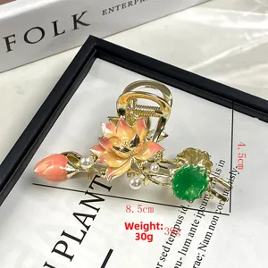 Dettaglio di elegante pinza per capelli a loto dorata con petali smaltati e perle