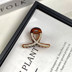 Close-up of a mini amber resin claw clip with sparkling rhinestones and metal spring detail