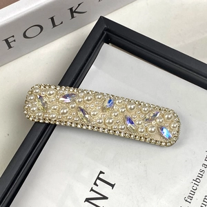 Elegant rectangle hair clip with pearls and rhinestones on a minimalist magazine background