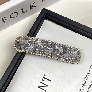 Elegant gold rectangle hair clip with grey pearls and marquise rhinestones on books