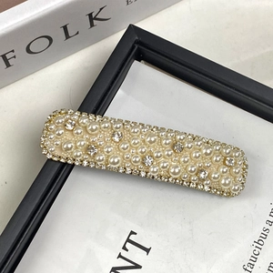Elegant gold hair clip with layered cream pearls and sparkling rhinestones on frame