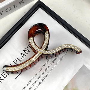 Macro view of a large tortoise resin hair claw with rhinestones and gold-tone edging