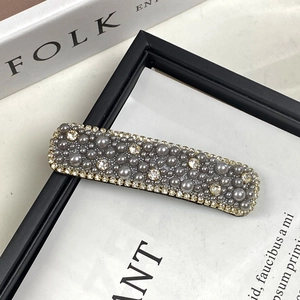 Detailed close-up of grey pearls and small rhinestones on a rectangle luxury hair clip