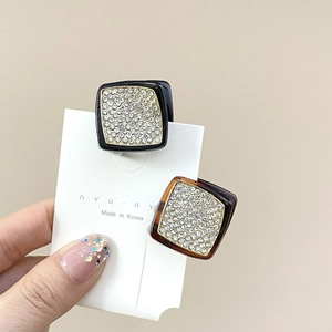 Détail de petites pinces à cheveux carrées avec strass en noir et finition écaille