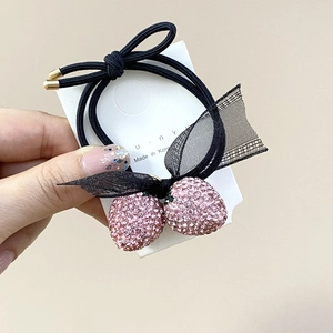 Détail de l'élastique à cheveux avec fraise en cristal rose, nœud en tulle et embouts dorés