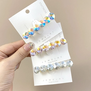 Detailed view of three shimmering crystal hair clips in blue, purple, and white colors