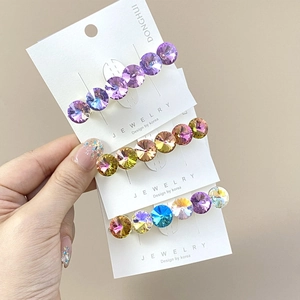 Detail showing three K9 crystal hair clips in lavender, champagne and rainbow colors
