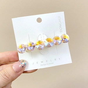 Detailed macro view of faceted AB crystal hair clip on a white jewelry display card