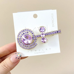 Detailweergave van goudkleurige lolly-haarklem met paarse strass en grote edelsteen