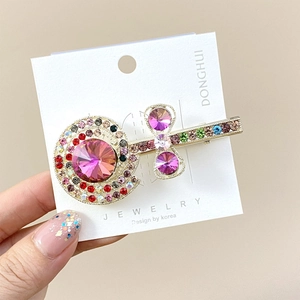 Detail van kleurrijke strass lolly haarspeld met roze edelsteen op een gouden basis