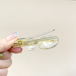 Detailopname van gouden legering haarklem met schelptextuur en geometrische accenten
